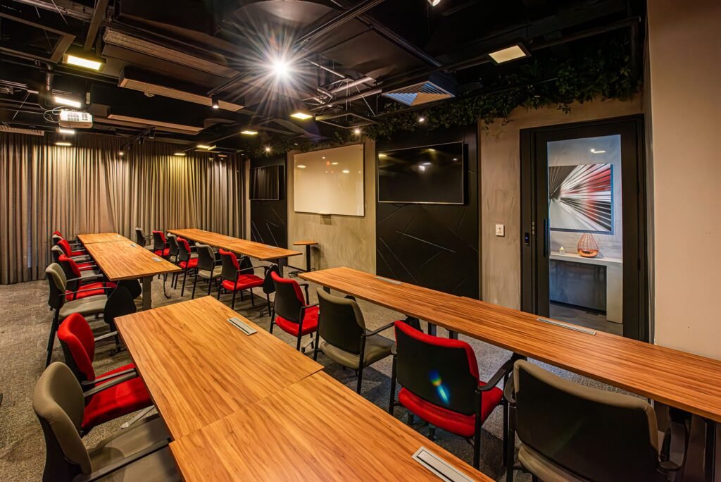 Sala de eventos do Club Coworking Paulista com mesas de madeira e cadeiras vermelhas